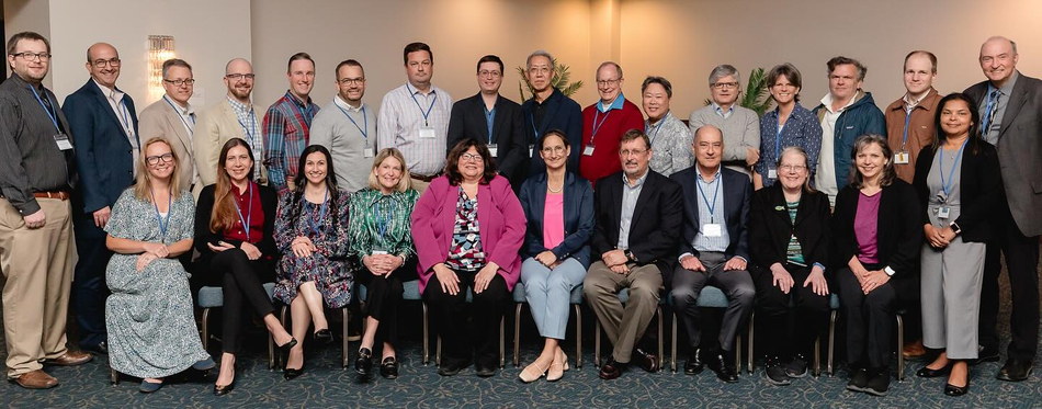 About thirty Beat Childhood Cancer Research Consortium physicians and principal investigators at a consortium meeting — one row seated, one row standing behind, all wearing name badges on lanyards.